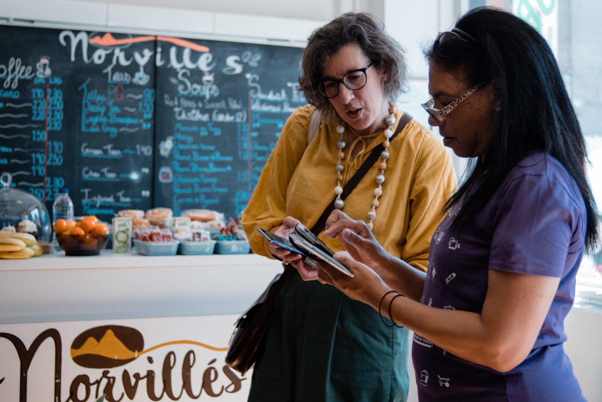 Two women look at an ipad in a cafe