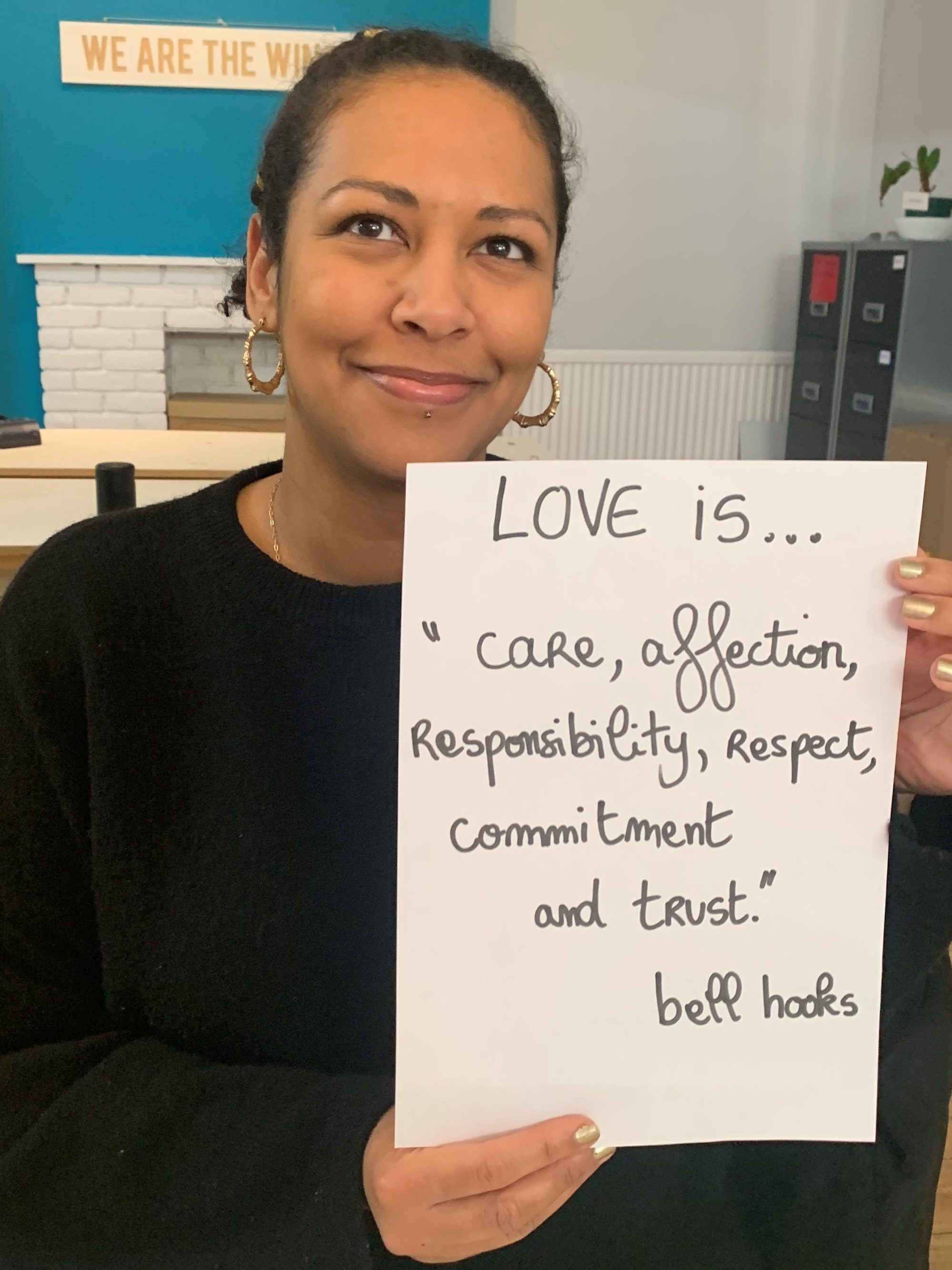 23_London_TheWinch_ProjectLove_PuP young woman holds up her handwritten poster which reads, Love is...care, affection, responsibility, respect, commitment and trust,